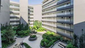 A multi-story residential building with balconies, a central courtyard with greenery, and a modern architectural design.