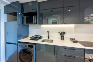 A modern kitchen with a washing machine, a microwave, and a sink.