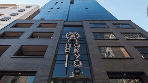 Ein hohes Gebäude mit einer auffälligen Beschilderung mit der Aufschrift 'TOKYO' und einem Logo darüber.