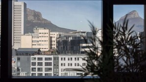 Eine Stadtansicht mit modernen Gebäuden und einem markanten Berg im Hintergrund.