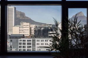 Eine Stadtansicht mit modernen Gebäuden und einem markanten Berg im Hintergrund.