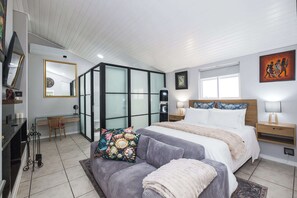A bedroom with a bed, bedside tables, a desk, a chair, a mirror, and a window. - Bishopscourt- Secret Garden hideaway (Cape Town)