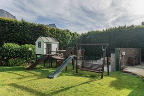 A playground with a slide, climbing structures, and a small building. - Bishopscourt- Secret Garden hideaway (Cape Town)