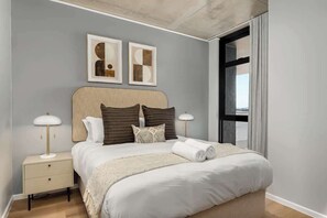 Ein modernes Schlafzimmer mit einem großen Bett, Nachttischen und Kunstwerken an der Wand.