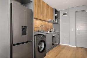 Eine moderne Küche mit Edelstahlgeräten, Holzschränken und einer integrierten Waschmaschine.