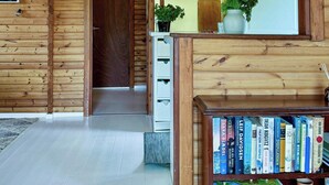 A wooden interior with a bookshelf, a door, and a hanging light fixture.