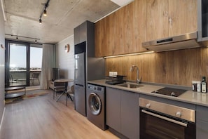 Eine moderne Küche mit Einbauwaschmaschine, Edelstahlbackofen und großem Fenster mit Blick auf eine Stadtlandschaft.