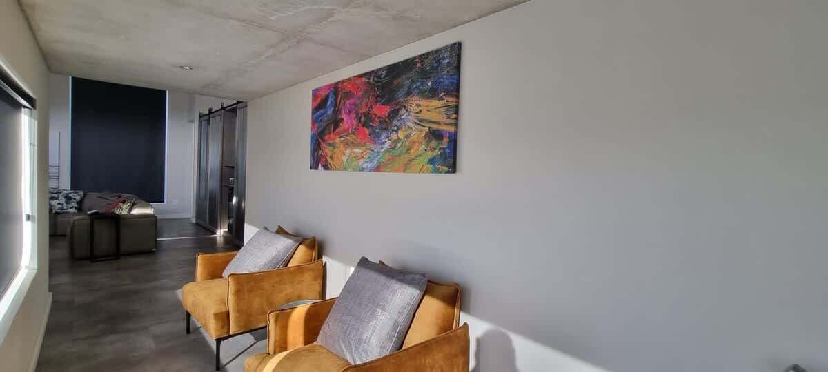 Un intérieur moderne avec un espace d’accueil comprenant un canapé et une peinture abstraite aux couleurs vives.