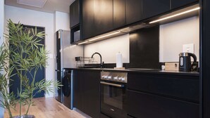 Une cuisine moderne avec des meubles de couleur noire, un four en acier inoxydable et un égouttoir à vaisselle.