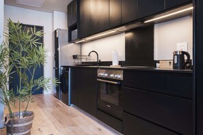 Eine moderne Küche mit schwarzen Schränken, einem Edelstahlbackofen und einem Geschirrgestell.