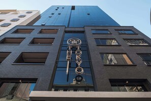 Ein hohes Gebäude mit einer auffälligen Beschilderung mit der Aufschrift 'TOKYO' und einem Logo darüber.