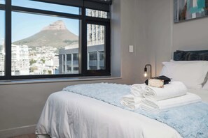 Ein Hotelzimmer mit Bett, Fenster mit Stadtblick und Wandleuchte.