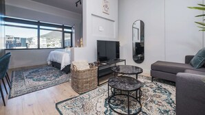 Un salon moderne avec un lit, une télévision, un canapé et de grandes fenêtres.