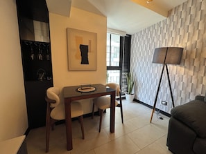 Un comedor con una mesa y sillas, una planta en maceta, una lámpara de pie y una pared con un diseño geométrico.