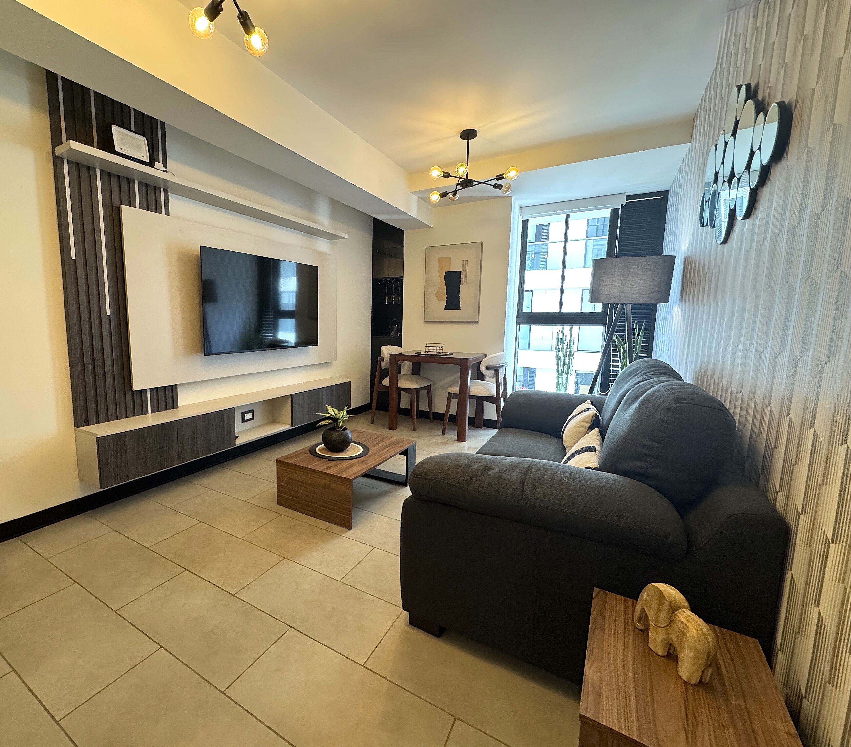 Una sala de estar moderna con un televisor de pantalla plana, un sofá, una mesa de centro y una zona de comedor.