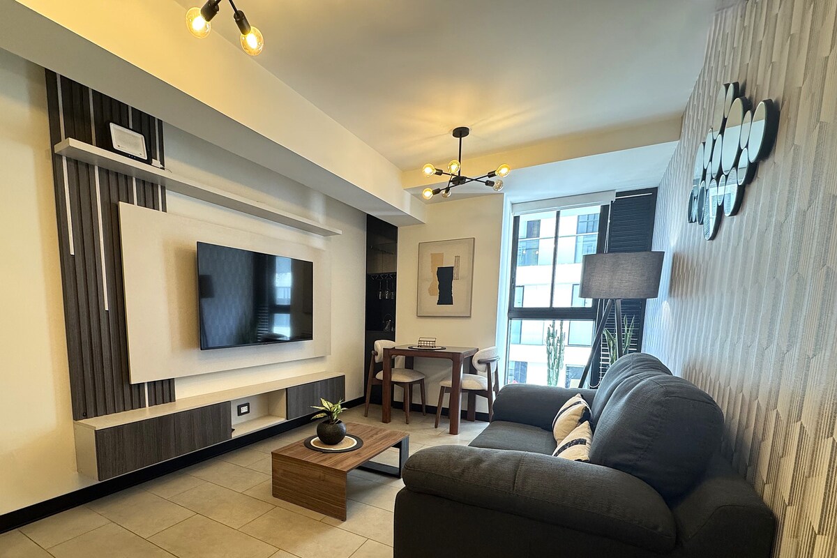 Una sala de estar moderna con un televisor de pantalla plana, un sofá, una mesa de centro y una zona de comedor.