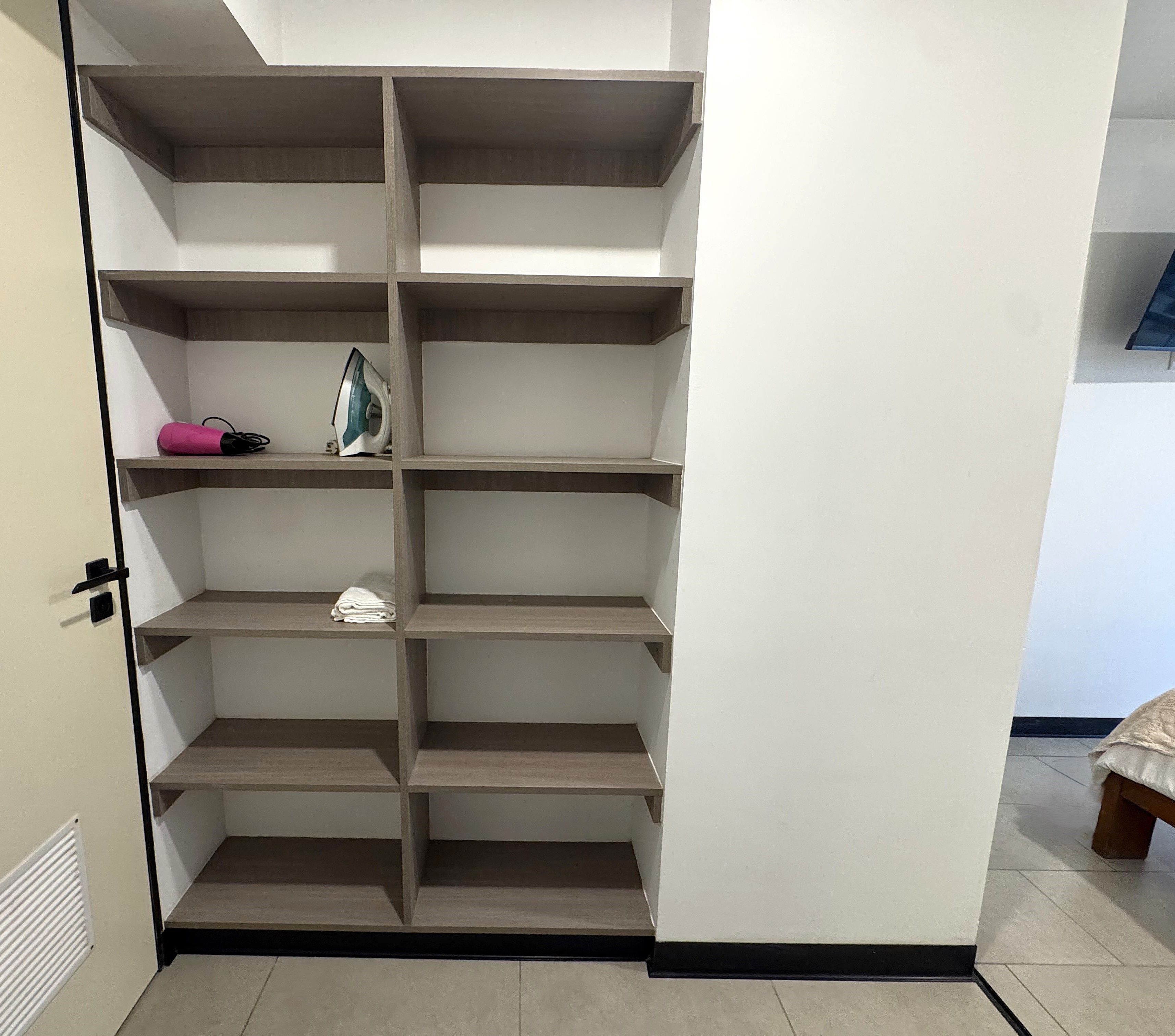 A walk-in closet with multiple shelves and a door.