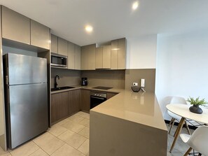 A modern kitchen with stainless steel appliances, a microwave, a coffee maker, and a dining area with a table and chairs. - Aparts4Days 1 Bedroom Apartment 548 (San Isidro)