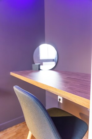 Une pièce avec un bureau en bois, un miroir rond et une chaise.