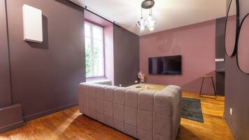 Een moderne woonkamer met een bank, een televisie, een raam en een houten vloer.