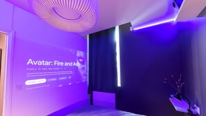 Ein modernes Schlafzimmer mit einem Bett, einem an der Wand montierten Projektor, der einen Film zeigt, und einer Deckenleuchte.