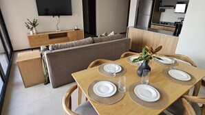En moderne stue med spiseplads, sofa, køkken og et fladskærms-tv.