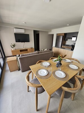 Ein moderner Wohnraum mit Essbereich, Sofa, Küche und Flachbildfernseher.