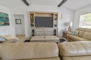 Ein Wohnzimmer mit Flachbildfernseher, einer Couch, einem Couchtisch und einer Vitrine.