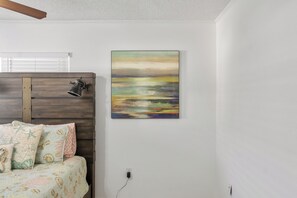 Ein Schlafzimmer mit einem Bett, einem Kopfteil, einer Wandlampe und einem Gemälde.