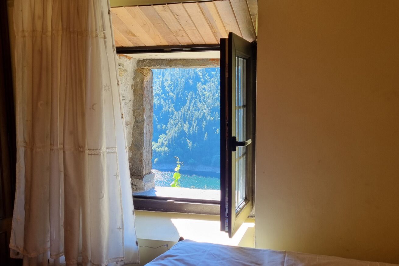 A room with a window, a curtain, and a bed.