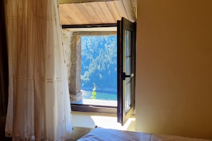 A room with a window, a curtain, and a bed.