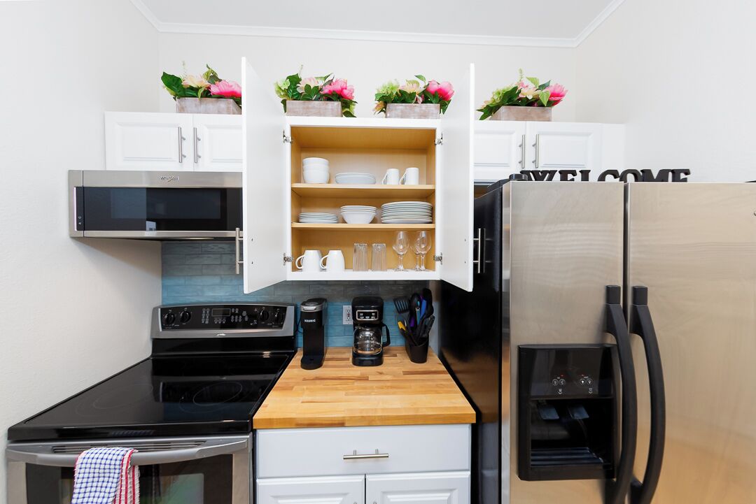 Una cocina equipada con microondas, estufa, cafetera y refrigerador.