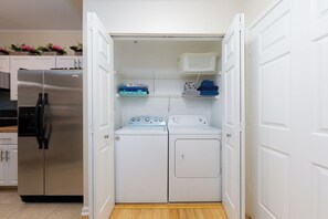 A compact laundry room with a stainless steel refrigerator, a washing machine, and a dryer.