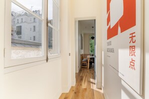 Ein Flur mit Holzboden, ein Essbereich mit Tisch und Stühlen sowie ein Fenster mit Blick auf ein Gebäude.