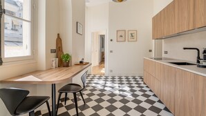 Une cuisine moderne avec un carrelage à motifs, des meubles en bois, un plan de travail noir et un luminaire suspendu.