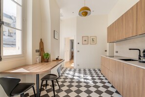 Eine moderne Küche mit Schachbrettboden, Holzschränken, einer schwarzen Arbeitsplatte und einer Pendelleuchte.