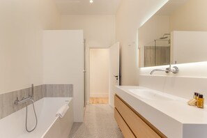 Et moderne badeværelse med badekar, bruser, vaskebord med spejl og toilet.