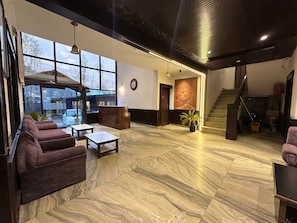 A spacious lobby with a reception desk, seating area, large windows, and a staircase. - Hotel Golden bees gym & spa (Srinagar)