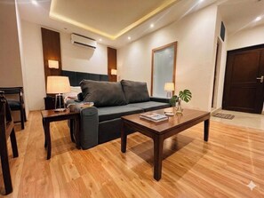 A modern living room with a sofa, coffee table, and lamps. - Hotel Golden bees gym & spa (Srinagar)
