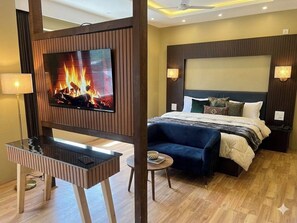 A modern hotel room with a TV, a bed, a sofa, a small table, and a lamp. - Hotel Golden bees gym & spa (Srinagar)