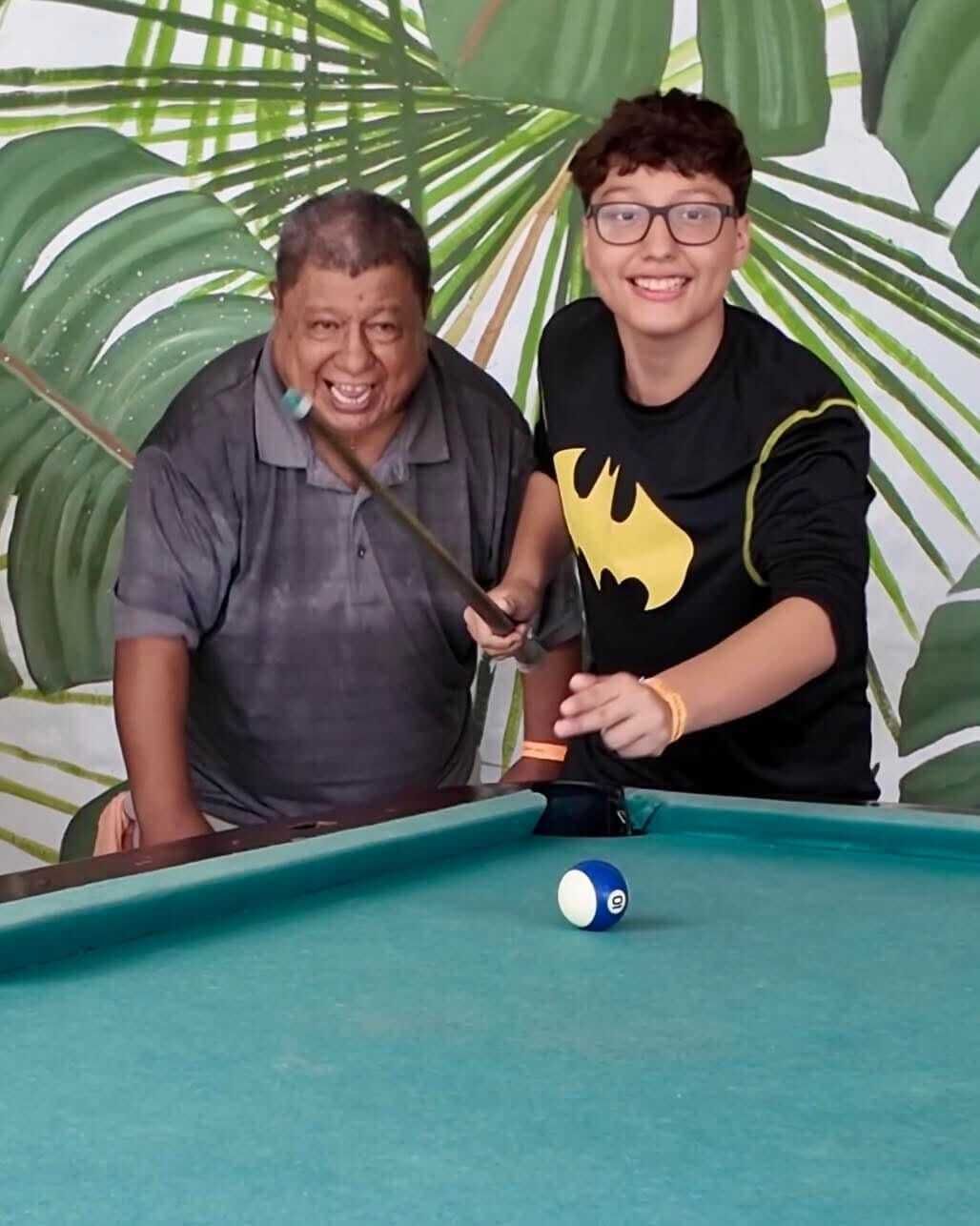 Zwei Personen spielen Billard an einem grünen Tisch mit einem blauen Ball.