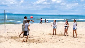 Ein Beachvolleyballspiel mit Spielern und Zuschauern am Sandstrand.