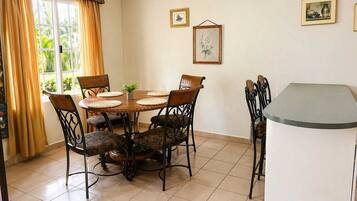 A dining area with a round table, six chairs, and a small potted plant.