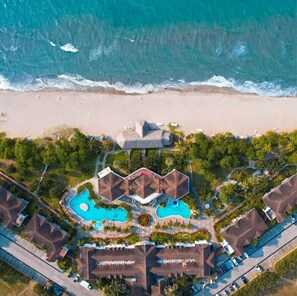 Oversigtsbillede af et resort med flere swimmingpools, direkte adgang til stranden og resortbygninger.