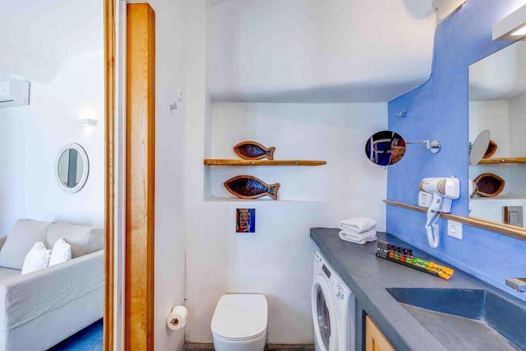 Ett modernt badrum med tvättmaskin, spegel och hyllor i form av fiskar, tillverkade av trä.