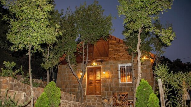 A stone building with a wooden door and windows, surrounded by trees. - Beel Hills - SOLARA (Mar Mikhael Bnabil)