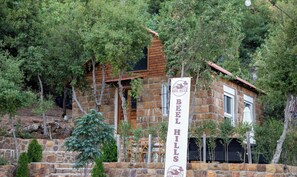 Edifício de pedra com placa indicando Beel Hills, rodeado por árvores.