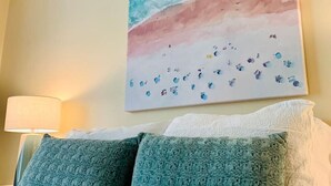 Ein Hotelzimmer mit Bett, Kissen, einem Wandbild und einer Nachttischlampe.