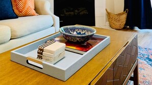 Ein Wohnzimmer mit Kamin, einer Couch, einem Couchtisch mit Tablett und einem dekorativen Spiegel.