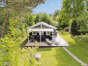 Ein Haus mit einer Terrasse, Sitzgelegenheiten im Freien und einem Garten.